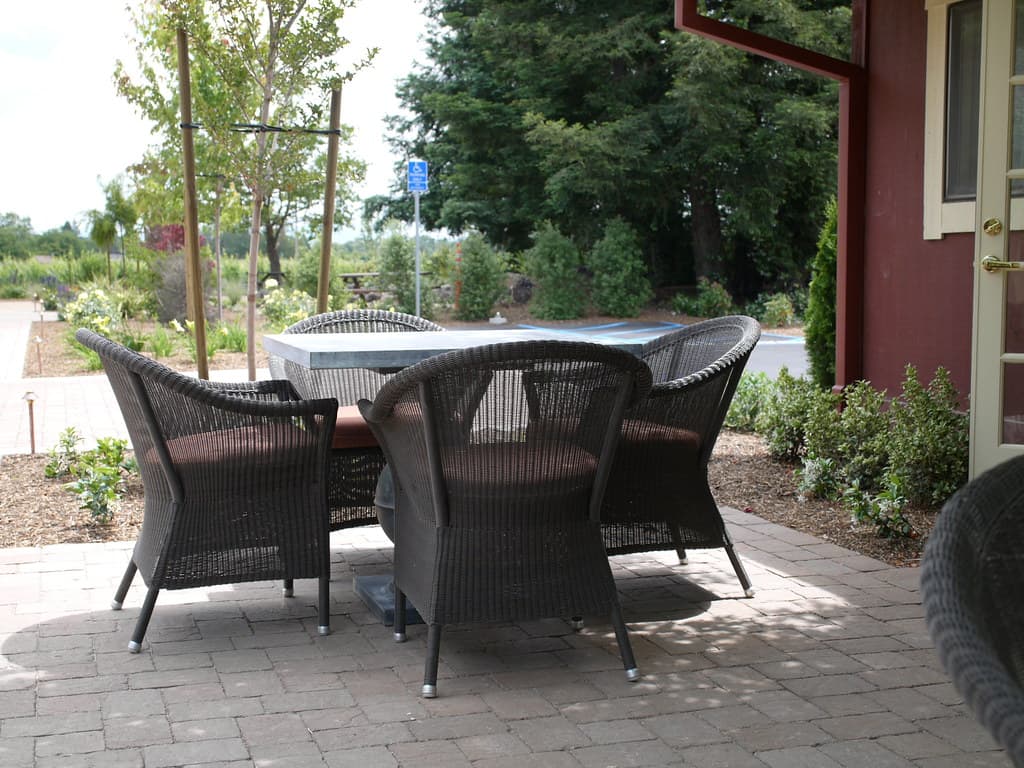 Wicker table and chairs on the terrace beside the red tasting room at DeLoach Vineyards