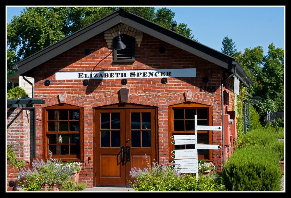 The small red-brick Elizabeth Spencer tasting room with arched wooden doors, lavender and a signpost out front