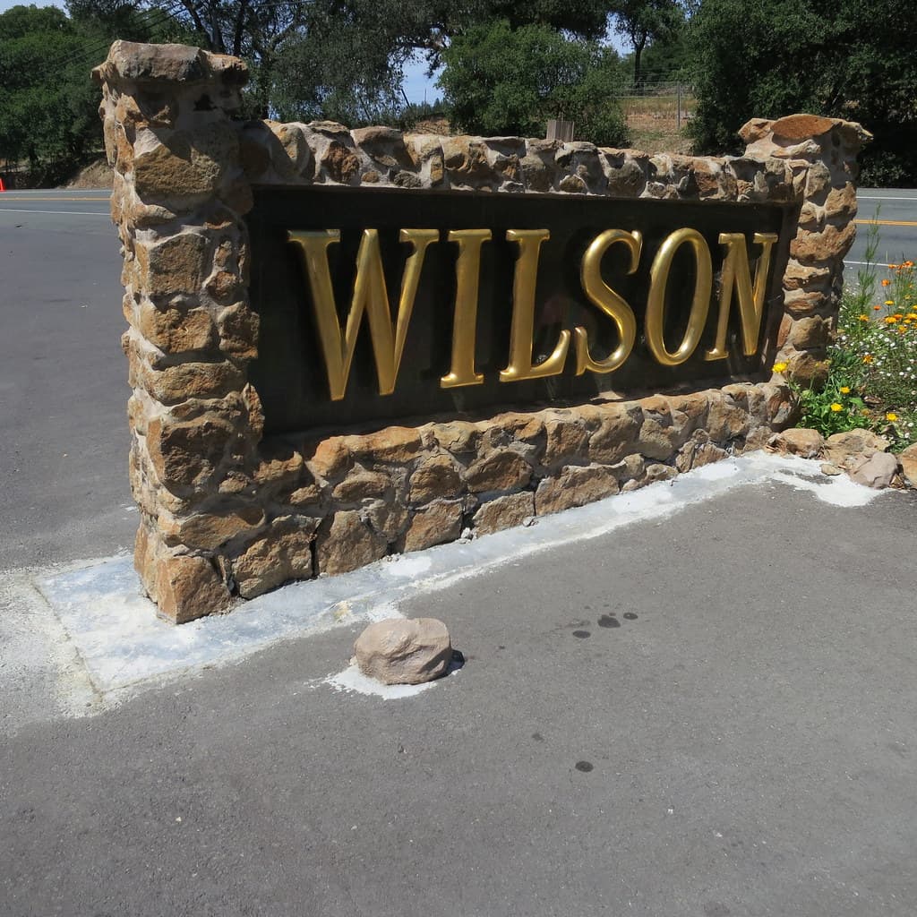 Fieldstone entrance sign with gold 'Wilson' lettering at the Wilson Winery driveway
