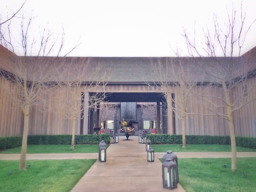 Lantern-lined walkway between lawns and young trees leading into the barn-style courtyard at Ram's Gate Winery