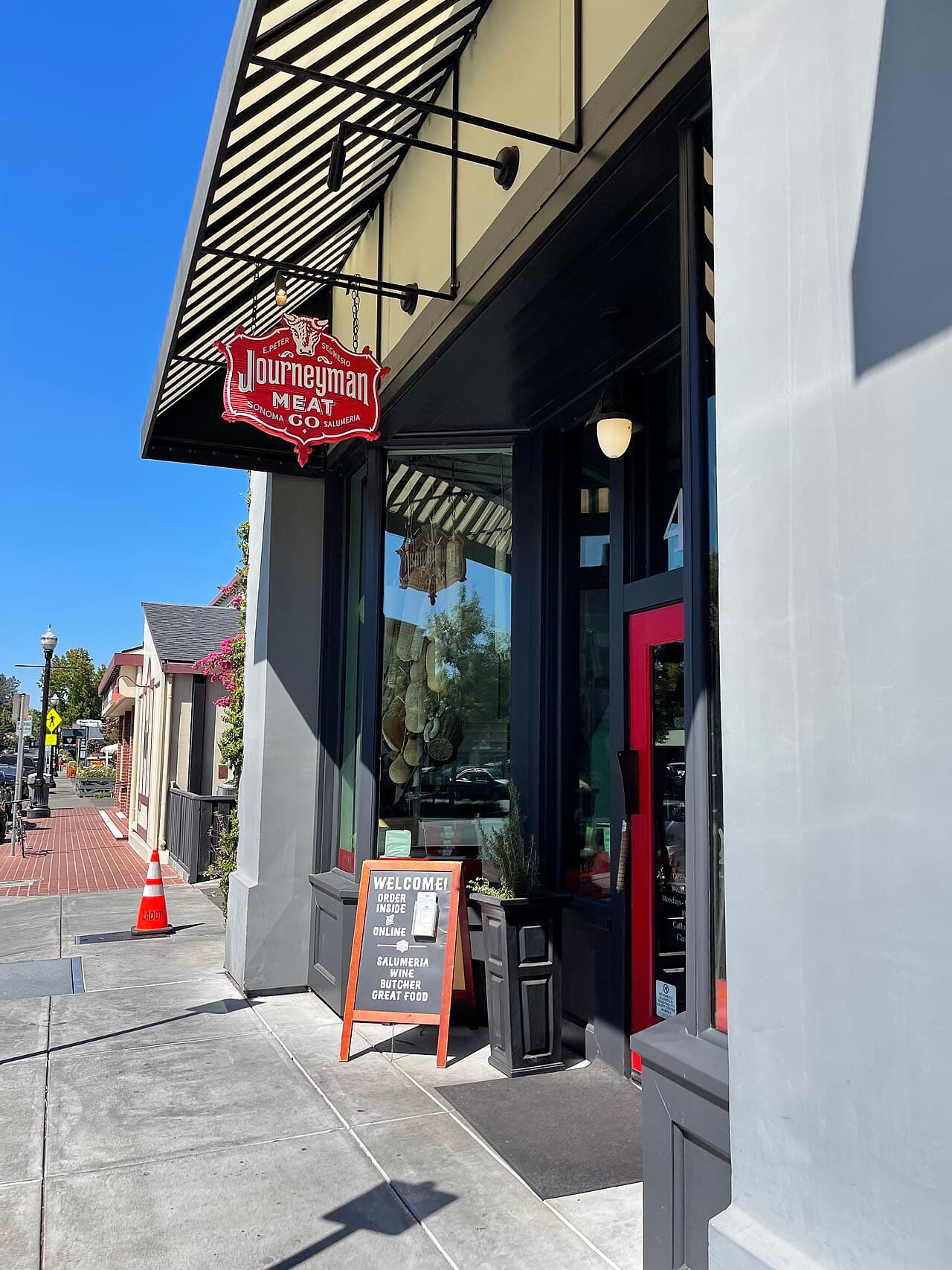 Journeyman Meat Co. storefront with its red sign and awning on a Healdsburg sidewalk