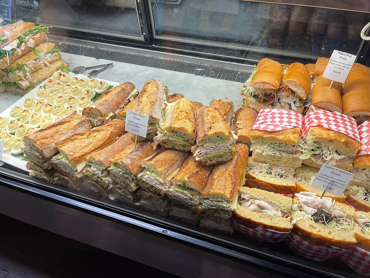 Deli case stacked with baguette sandwiches wrapped in gingham paper at the Dry Creek General Store