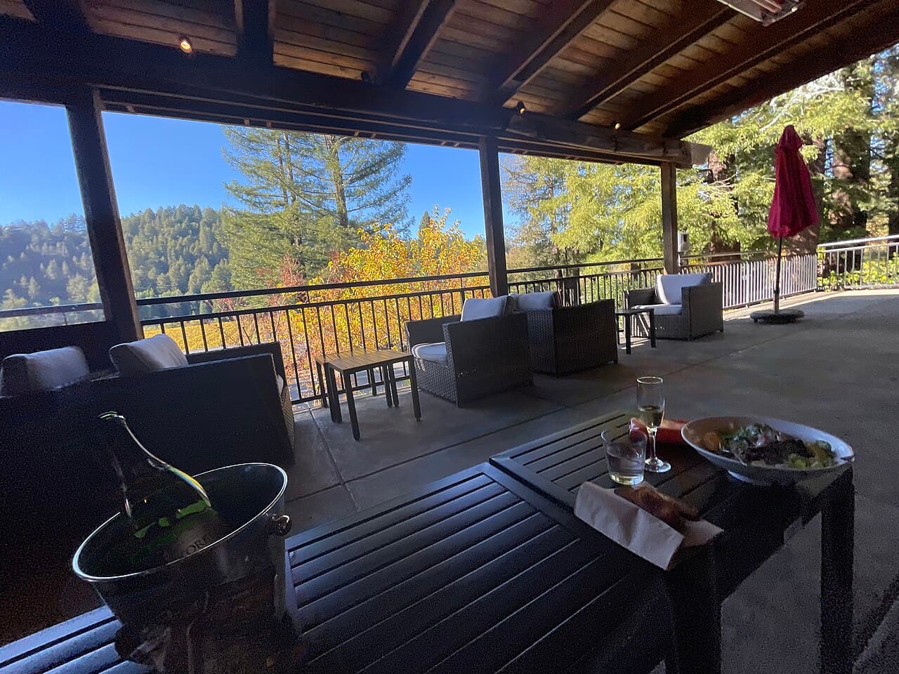 Shaded deck with lounge chairs and tables overlooking redwoods and autumn trees at Korbel Champagne Cellars