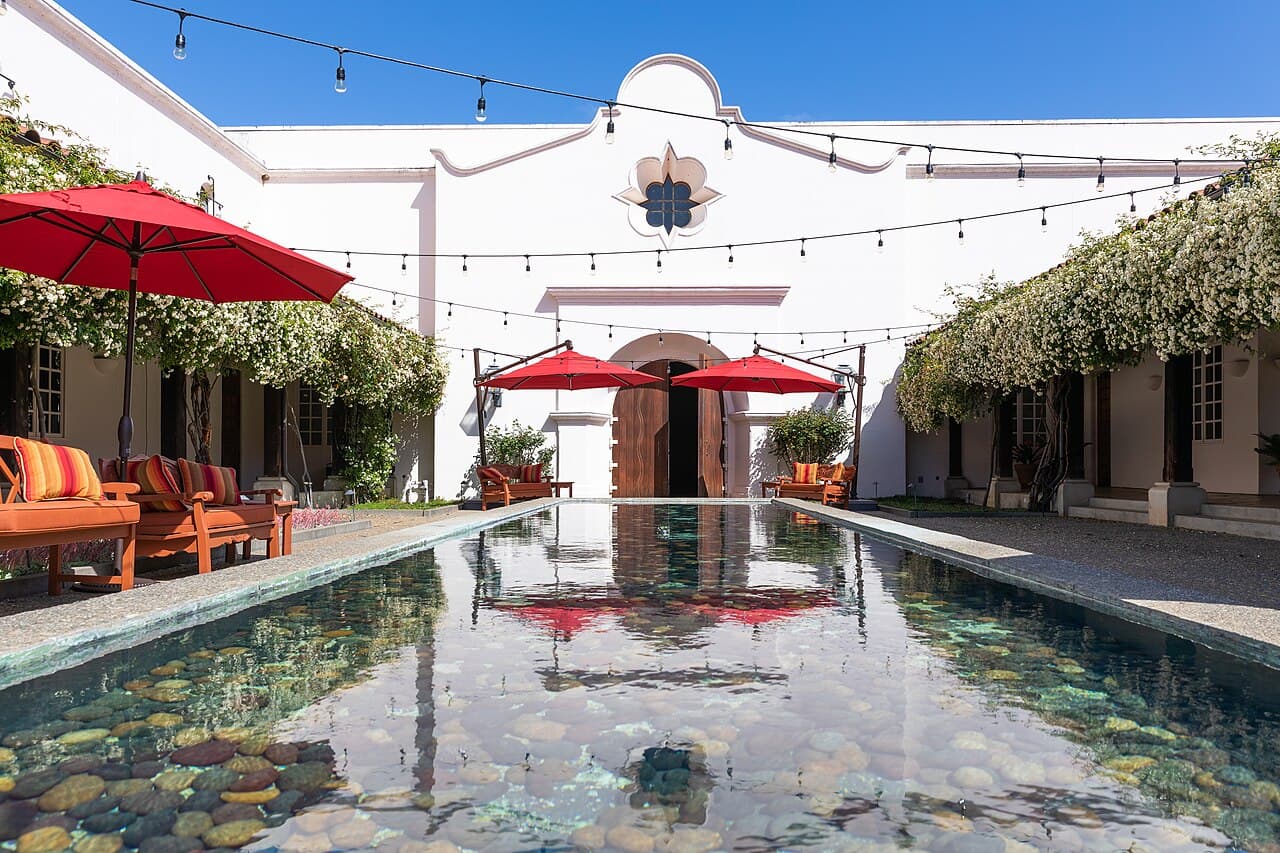 Mission-style inner courtyard with a reflecting pool, red umbrellas and string lights at Michel-Schlumberger