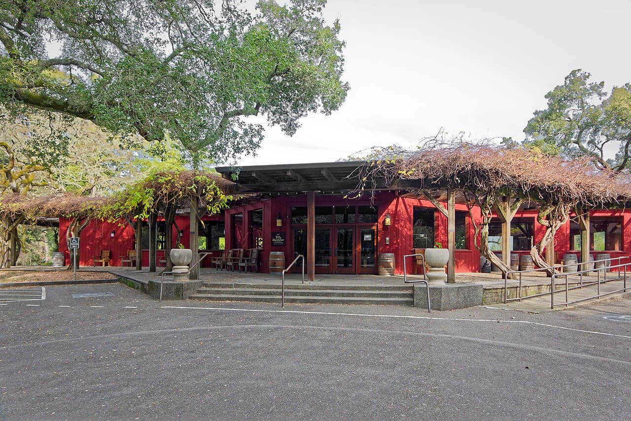 Red Villa Chanticleer hall with wisteria-covered pergolas under oaks in Healdsburg