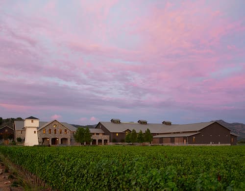 Silver Oak Cellars in Oakville at dusk, with its stone winery buildings and water tower under a pink sky