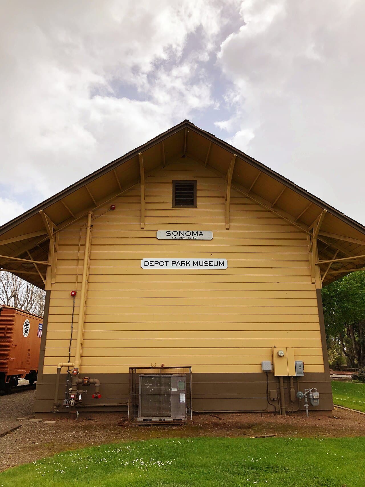Yellow Sonoma depot building, now the Depot Park Museum, on a lawn at Depot Park