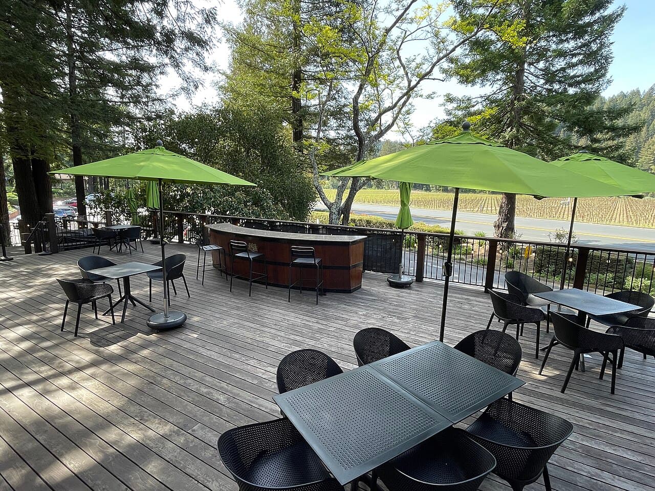 Outdoor deck with tables and green umbrellas looking toward vineyards at Korbel Champagne Cellars