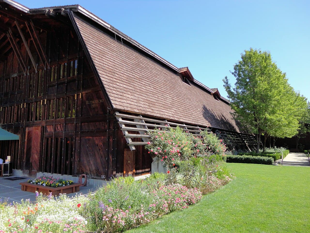Redwood barn-style Rutherford Hill winery building with rose beds and a broad green lawn