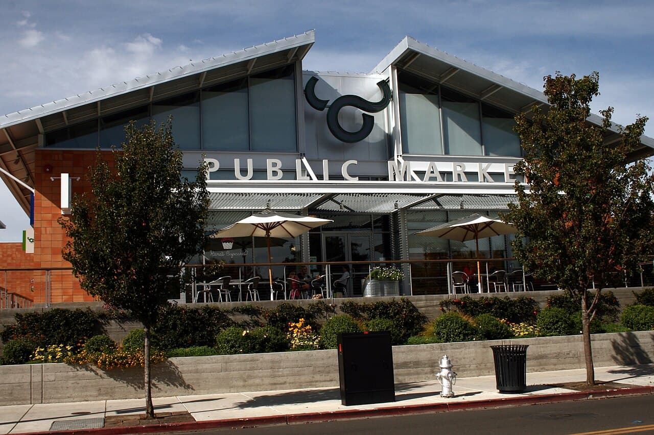 Oxbow Public Market's front with its big Public Market sign and an outdoor patio of tables under umbrellas above the street