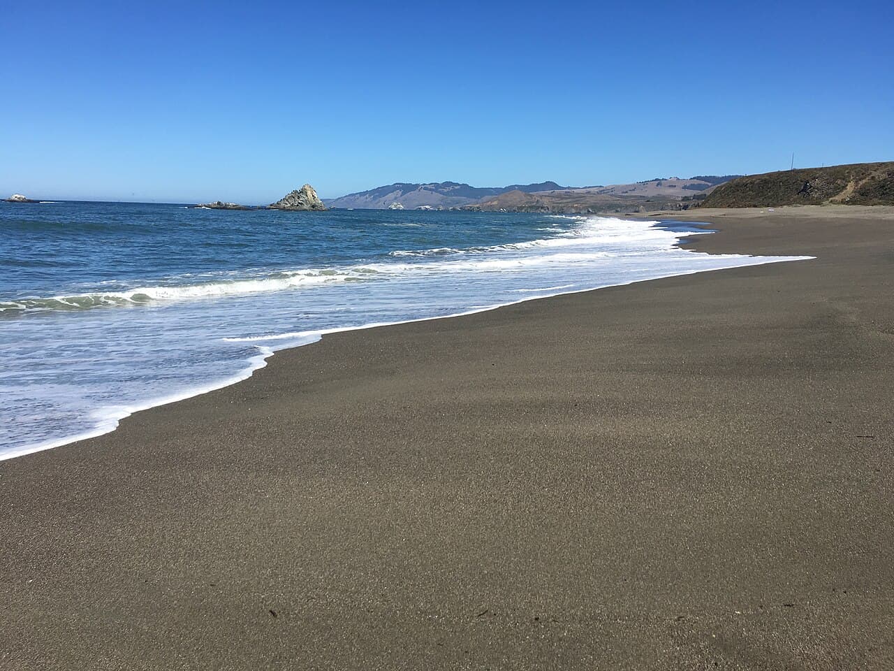 Wide sandy beach, gentle surf and offshore rocks at Wright's Beach on the Sonoma Coast