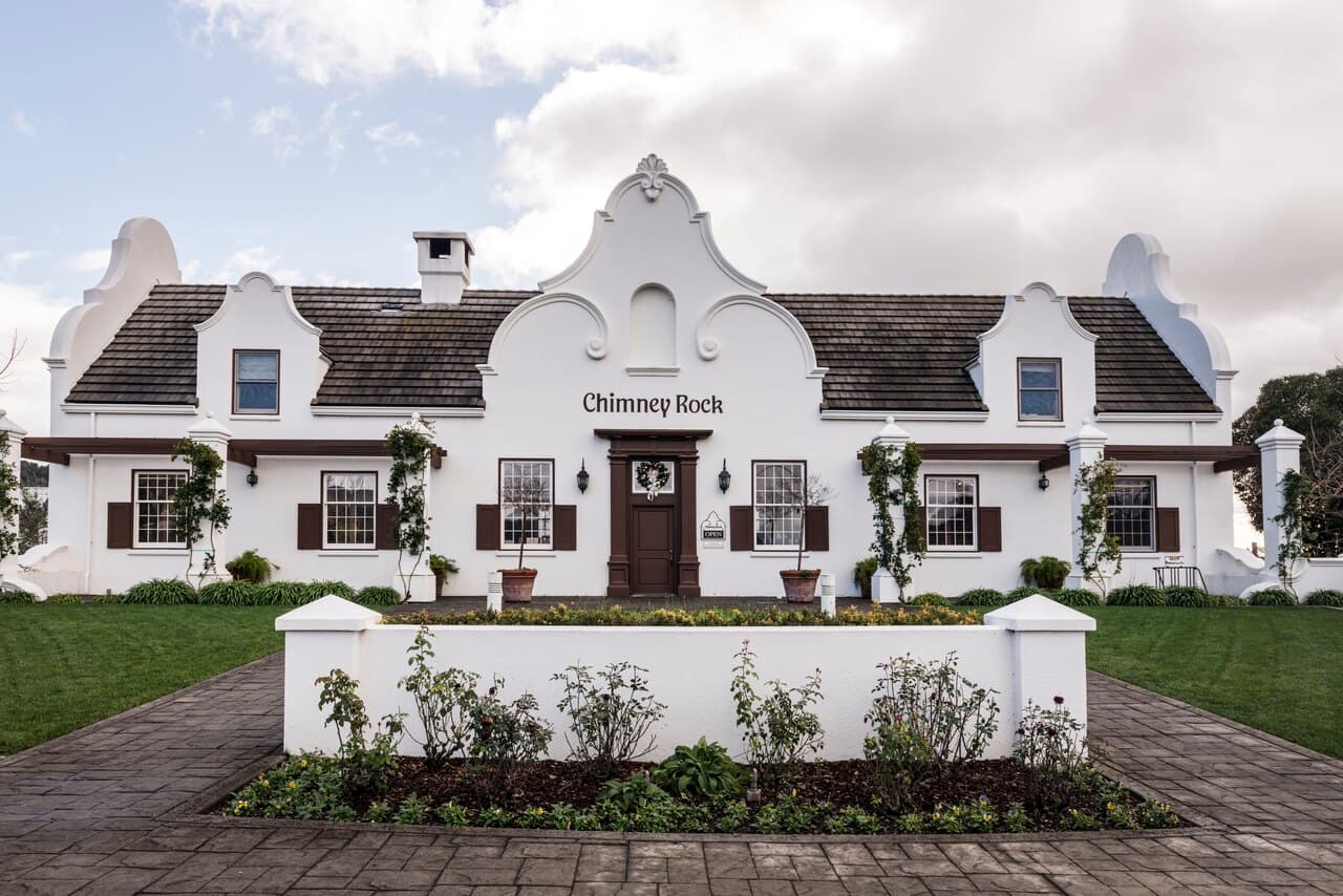 The white Cape Dutch-style Chimney Rock winery building with its curved gables, lawn and a planter out front