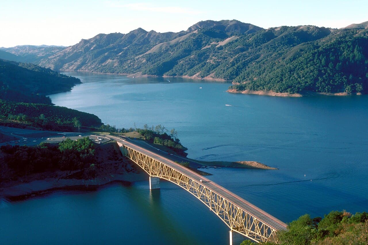 Blue water of Lake Sonoma winding between forested hills, crossed by the arched Warm Springs Creek bridge