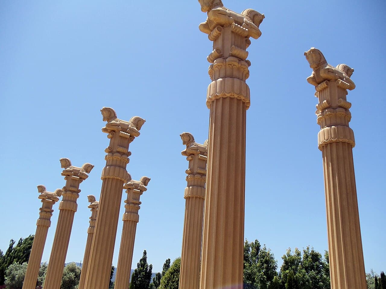 Persepolis-style columns topped with bull capitals rising against a clear blue sky in the entrance garden at Darioush Winery