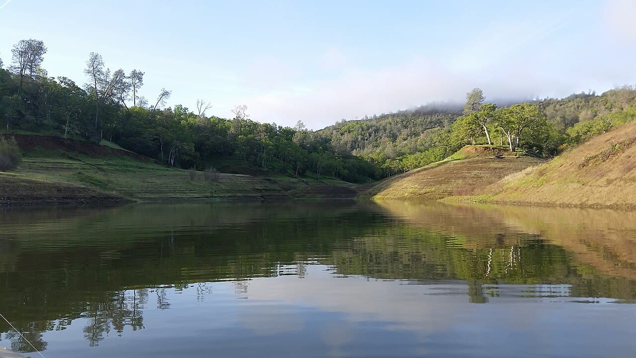 Still cove of Lake Berryessa reflecting oak-covered hills at Smittle Creek, seen from a kayak