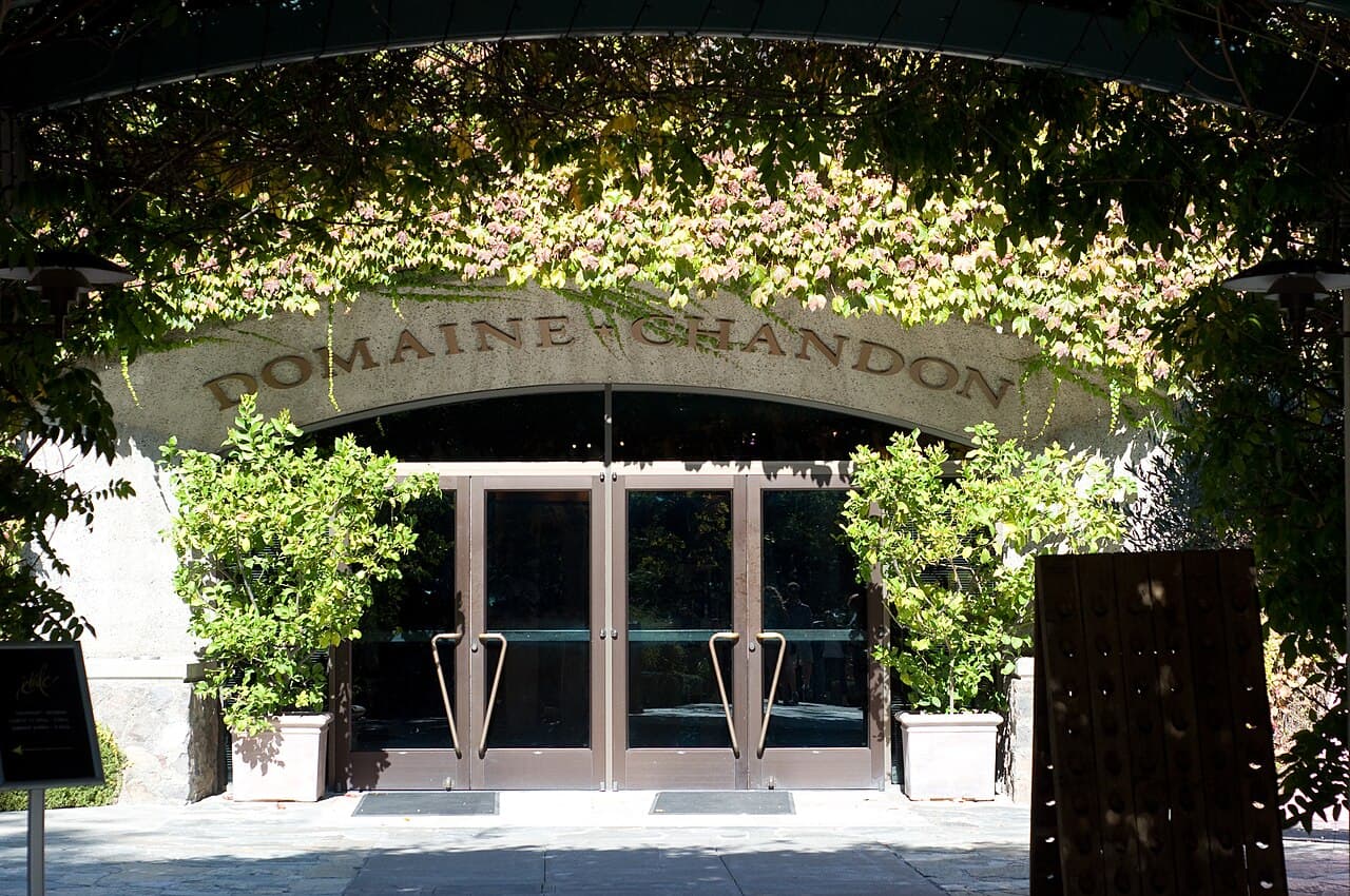 Vine-draped arched entrance with Domaine Chandon lettering above the glass doors at the Yountville estate