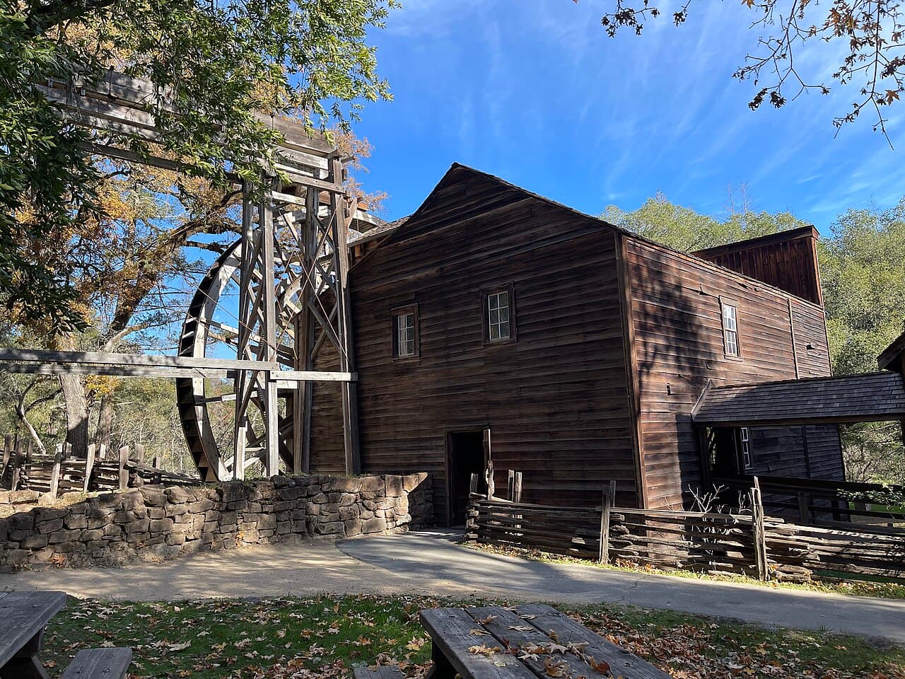 Picnic tables on the lawn facing the wooden grist mill and its giant waterwheel at Bale Grist Mill State Historic Park