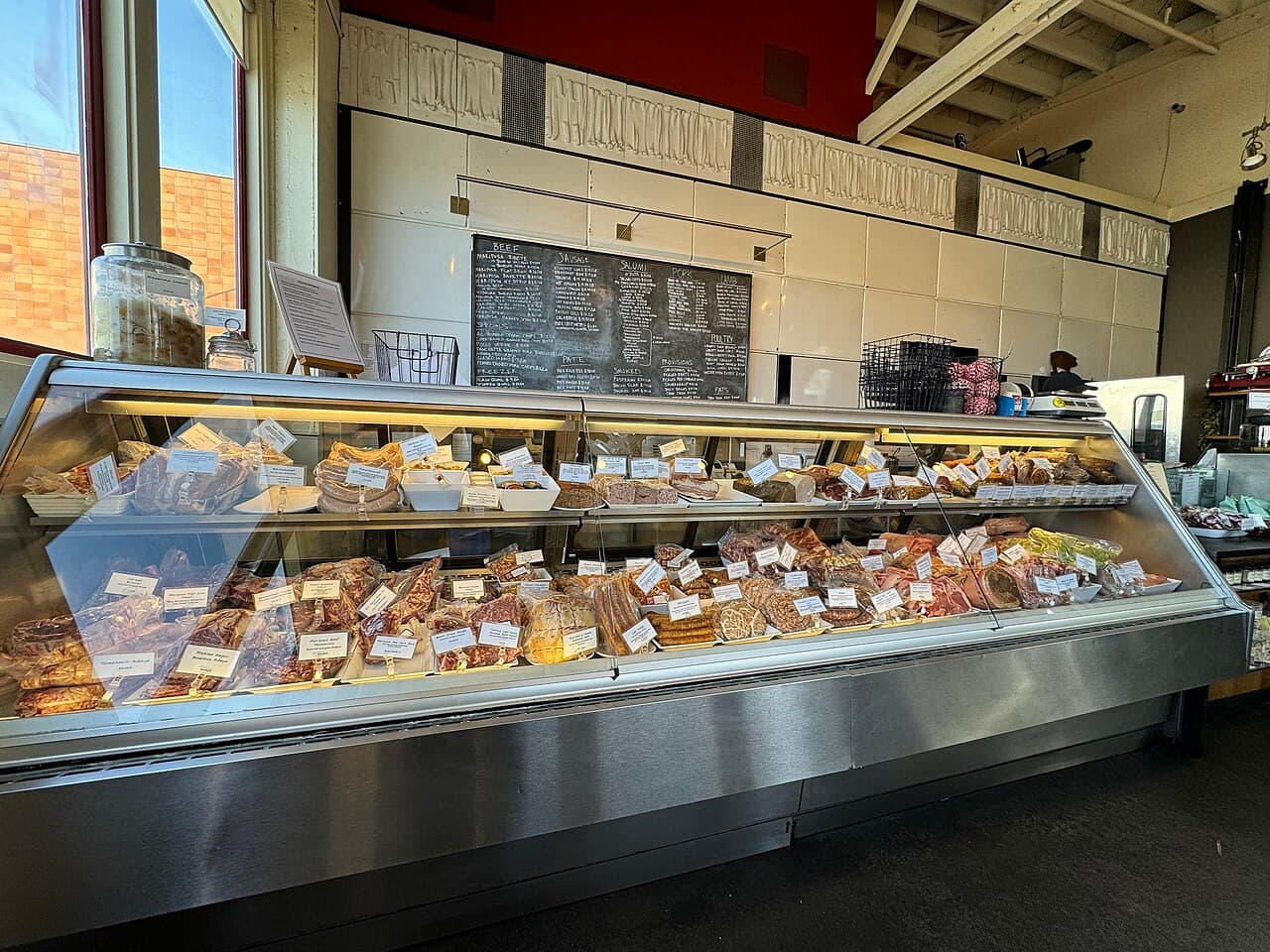 Long glass case of house-made charcuterie, sausages and terrines under the chalkboard menu at Fatted Calf in Napa