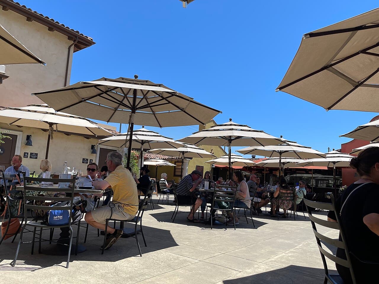 Sunny Tuscan-style courtyard with umbrella-shaded tables where guests eat at VJB Vineyards & Cellars