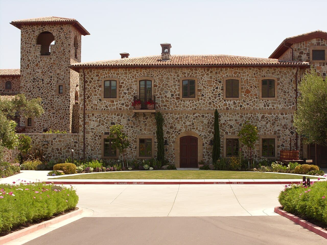 Stone Italian-villa-style Jacuzzi Family Vineyards winery with its tower, lawn and front drive