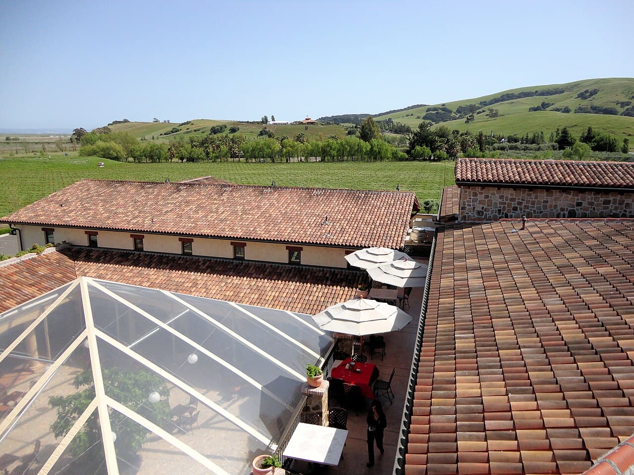 View over the tiled roofs and umbrella-shaded piazza of Jacuzzi Family Vineyards to Carneros vineyards and green hills